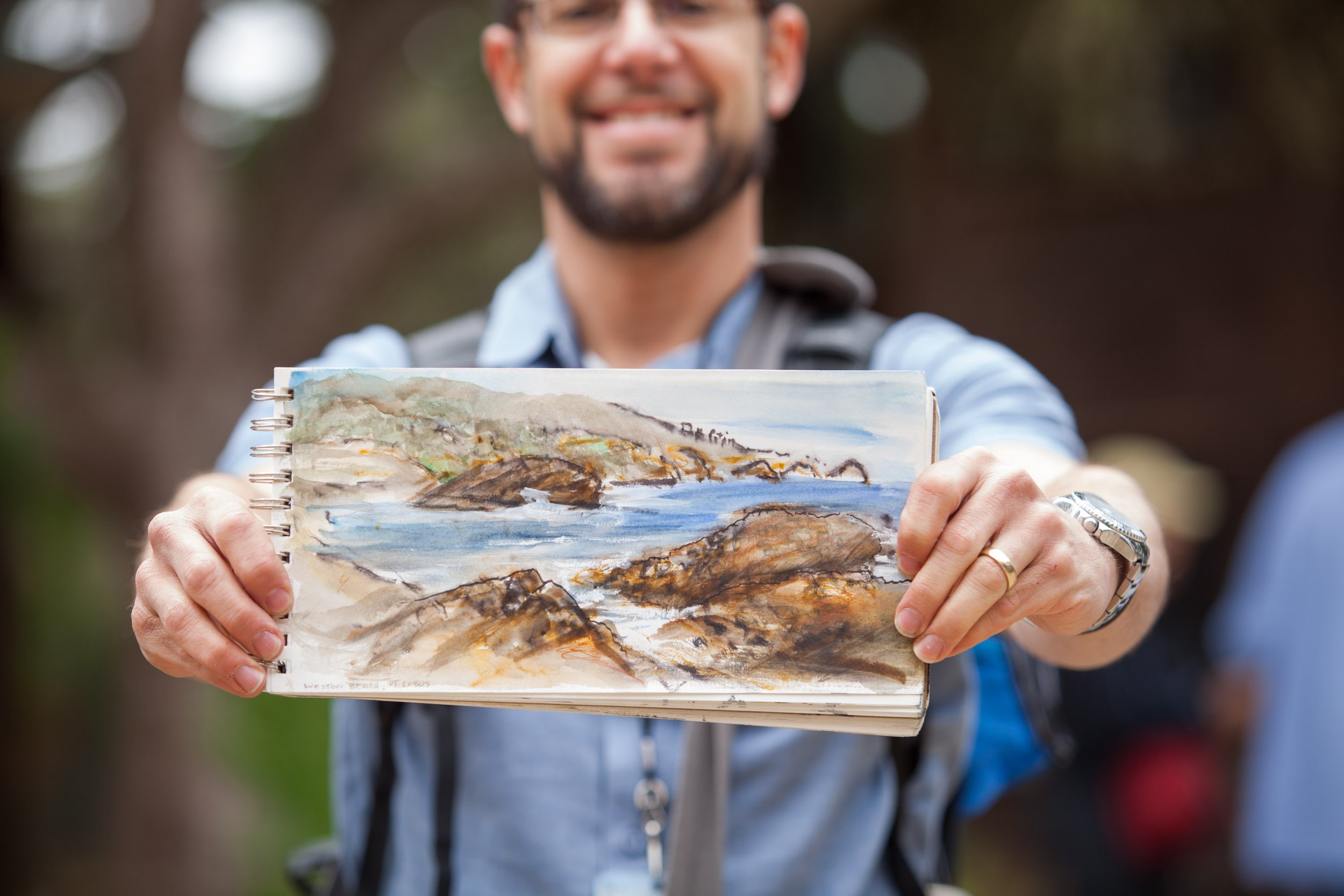 John Wolf holding up a picture of his nature journaling page of the coast during a Wild Wonder Foundation event